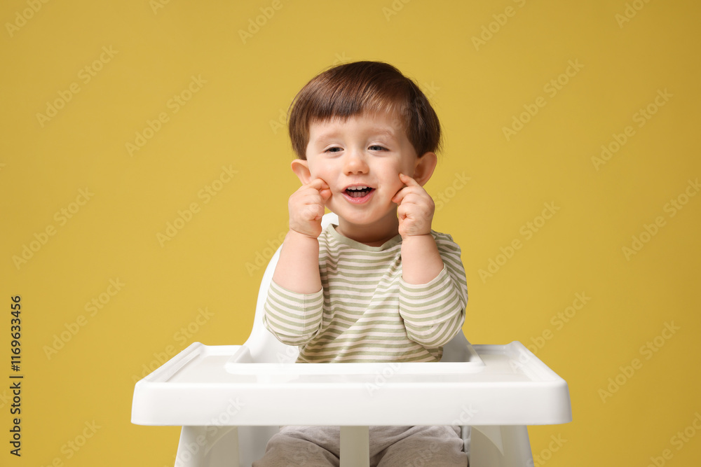 Cute little kid sitting in high chair on yellow background Cute little kid sitting in high chair on yellow background