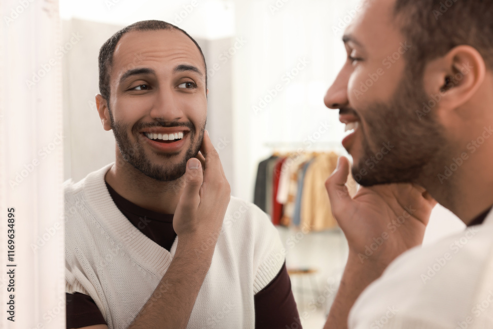 Smiling man looking at mirror at home Smiling man looking at mirror at home