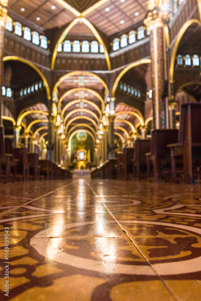 Obraz premium Vertical photo of wide central hallway with classical architecture with wooden benches of the Basilica of Our Lady of the Angels in Cartago, Costa Rica
