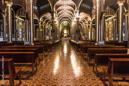 Wide central hallway with classical architecture with wooden benches from the Basilica of Our Lady of the Angels in Cartago, Costa Rica photo