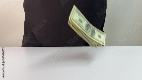 Hands are skillfully counting several bills, arranged neatly on a clean white surface, while additional banknotes appear to fall, enhancing the moment of financial focus.