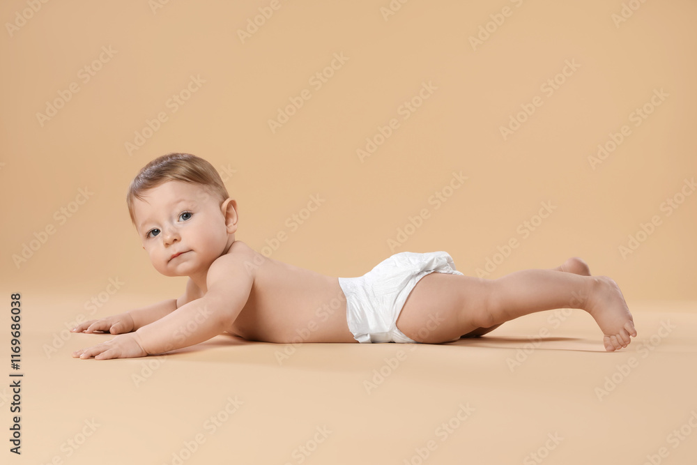 Obraz premium Cute little baby in diaper crawling on beige background
