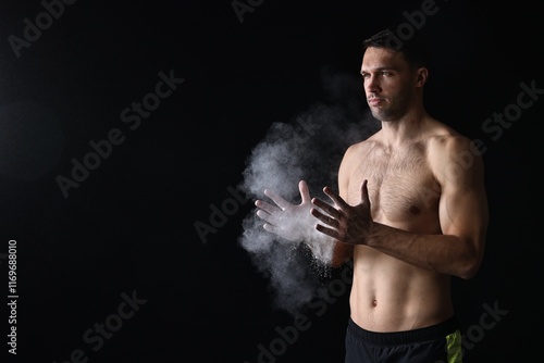 Man clapping hands with talcum powder before training on black background. Space for text photo