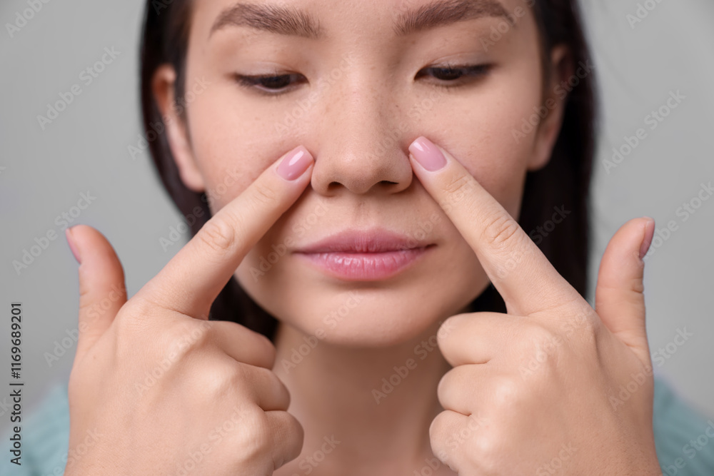 Woman touching her nose on light grey background, closeup Woman touching her nose on light grey background, closeup