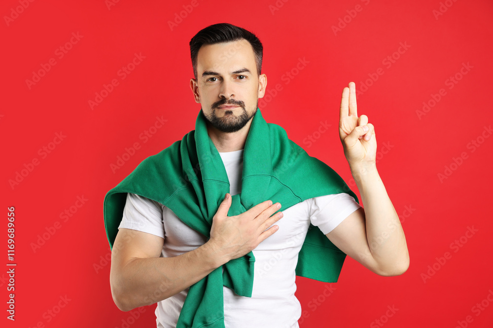 Fototapeta premium Man showing oath gesture on red background. Making promise