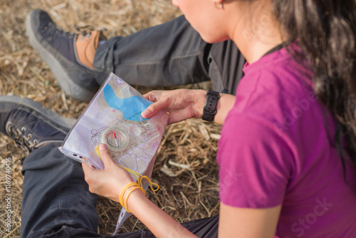 Woman reading map and holding compass during orienteering race. Latin young venezuelan