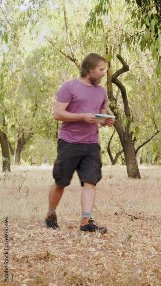 Orienteering runner completing a checkpoint in a park Orienteering runner completing a checkpoint in a park