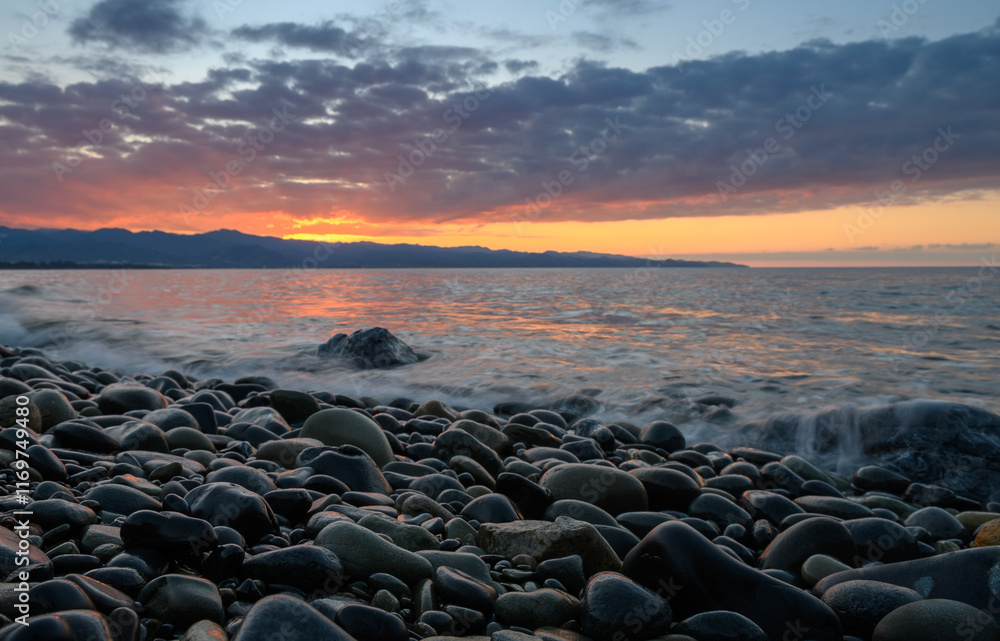 Sunset reflections on shimmering pebbles along the tranquil shoreline Sunset reflections on shimmering pebbles along the tranquil shoreline