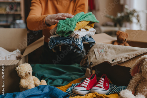 Tableau sur toile Woman sorting an old out-of-use kid toy, clothes and shoes in box for charity or