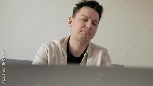 Young man feeling stressed while working on computer in a modern home interior. Disappointed man close the laptop and lay on sofa