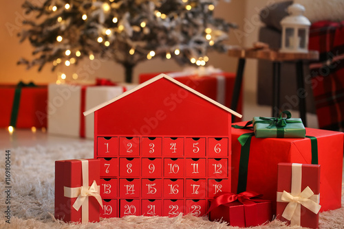 Red advent calendar with gift boxes on floor near Christmas tree at home