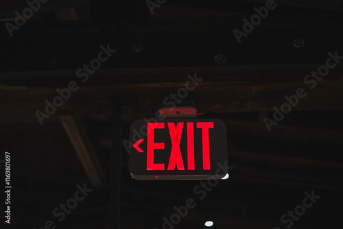 red light up exit sign with arrow in a dark room