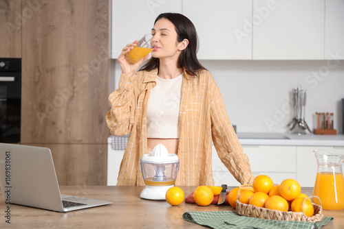 Young woman drinking sweet orange juice in kitchen photo