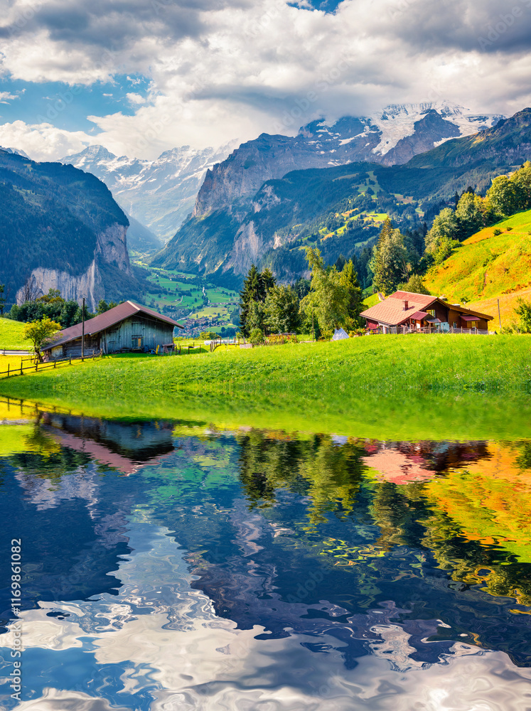 Green pasture and wooden chalets of Wengen village reflected in the calm waters of small mountain pond. Splendid summer scene in Swiss Alps. Beautiful morning scene of Switzerland, Europe.