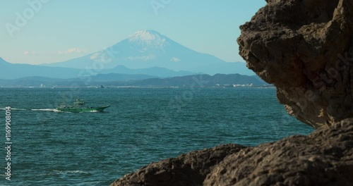 fishing boat returning across Sagami Bay, framed coastal rocks, Mount Fuji Japan photo