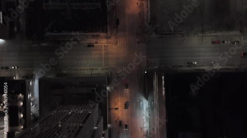 Overhead nighttime view of a busy city intersection in downtown, featuring streetlights, vehicles and urben architecture illuminated by city lights photo