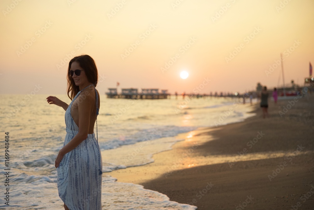 Smiling Woman Strolling Along Sunset Beach with Gentle Waves and Scenic Pier Smiling Woman Strolling Along Sunset Beach with Gentle Waves and Scenic Pier