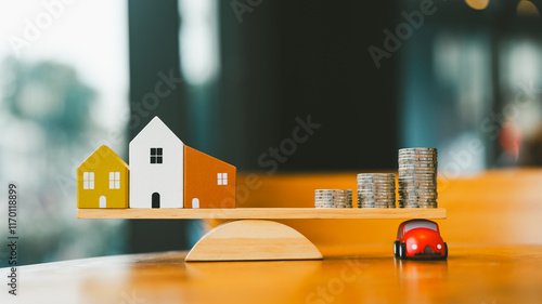 A wooden balance with a house and a pile of money on opposite sides with a car model under the pile of money. The idea is to trade your car for cash to pay for your house. photo