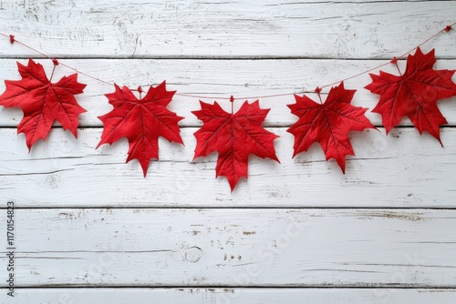 Festive red maple leaves and bunting garland arranged on a white wooden background with copy space, perfect for celebrating Canada Day.  . photo