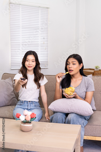 Two friends enjoying snacks while watching TV in a cozy living room.