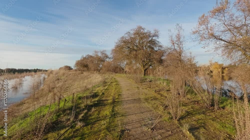 Walking on a levee in winter at sunset alone Walking on a levee in winter at sunset alone