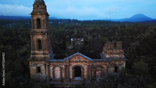 Aerial approaching shot of San Juan Parangaricutiro Church, Mexico. Historic old church during cloudy day. photo