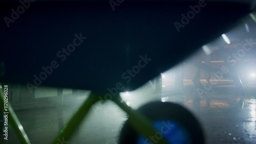 Tracking shot following little robot car through hazy warehouse and beneath objects