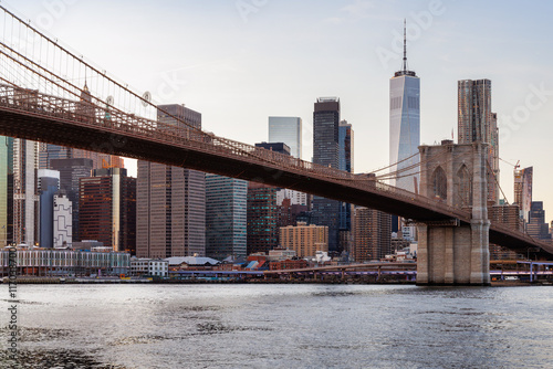 A panoramic sunset view of the Brooklyn Bridge stretching towards Manhattan