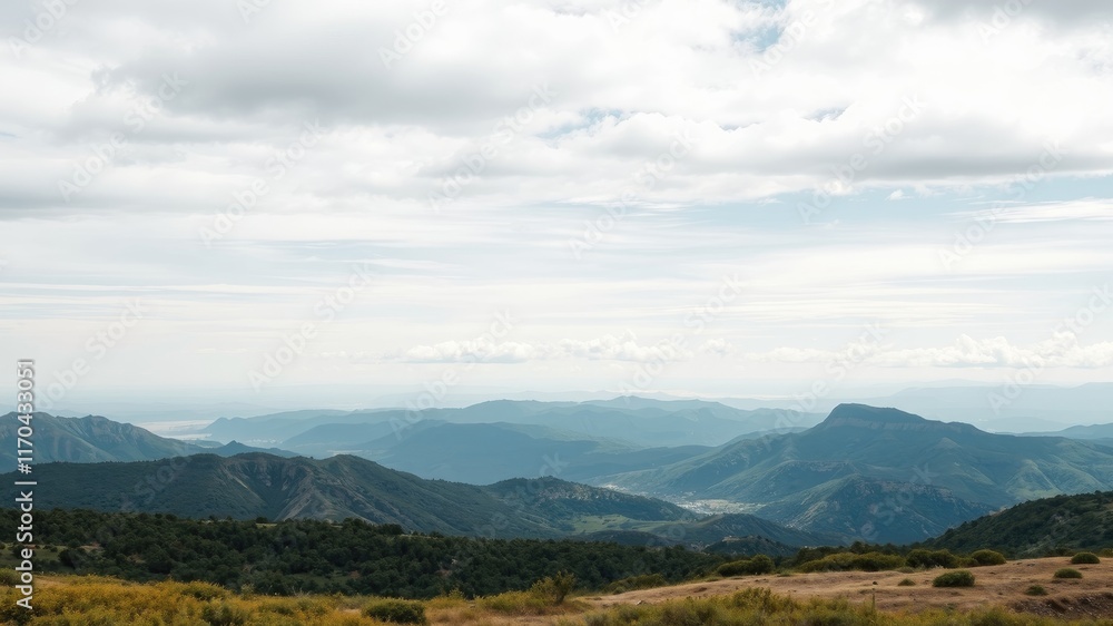 Serene Vista of Rolling Hills and Distant Mountains Under a Cloudy Sky Serene Vista of Rolling Hills and Distant Mountains Under a Cloudy Sky