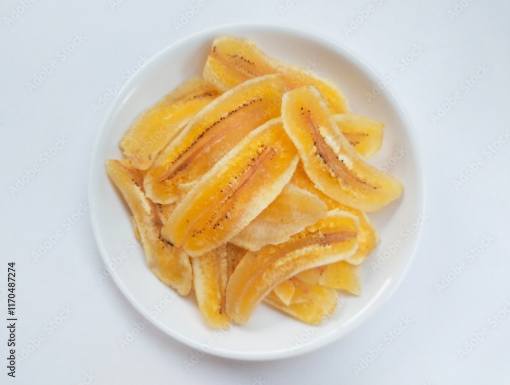 Close-up of banana chips in plate on white background. Close-up of banana chips in plate on white background.