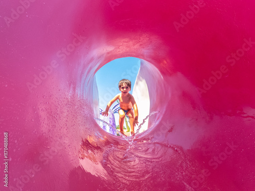 Slika na platnu Child sliding down pink waterslide at water park, summer vacation fun