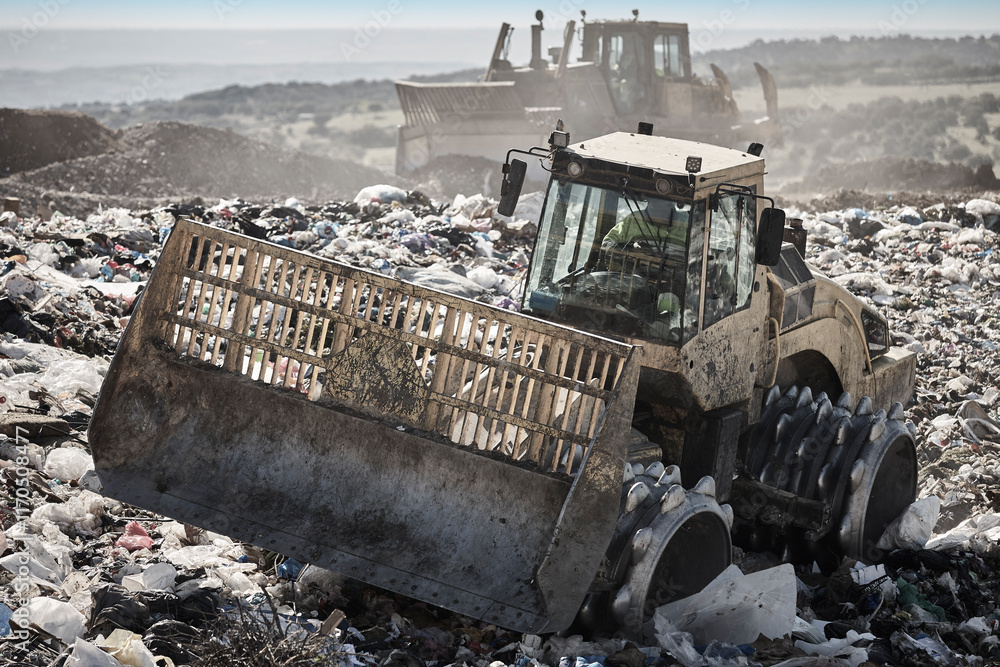 Heavy machinery shredding garbage in an open air landfill. Pollution
