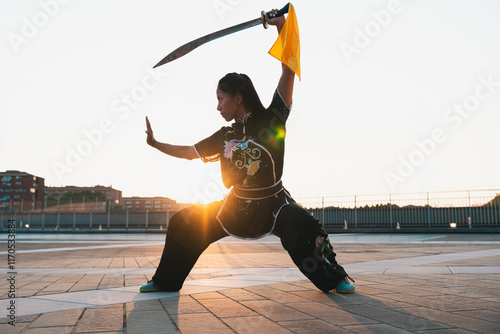 Quadro su tela Chinese young woman practicing wushu kung fu with weapons outdoor
