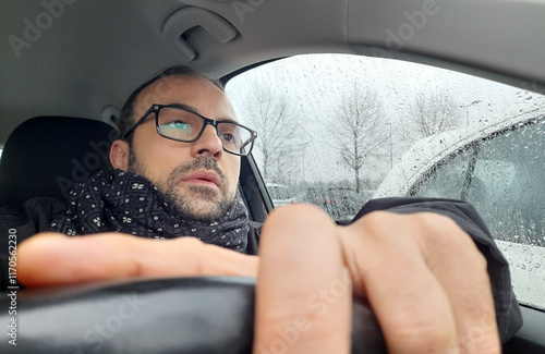 Autista alla guida della propria automobile in una giornata di pioggia in inverno	 photo