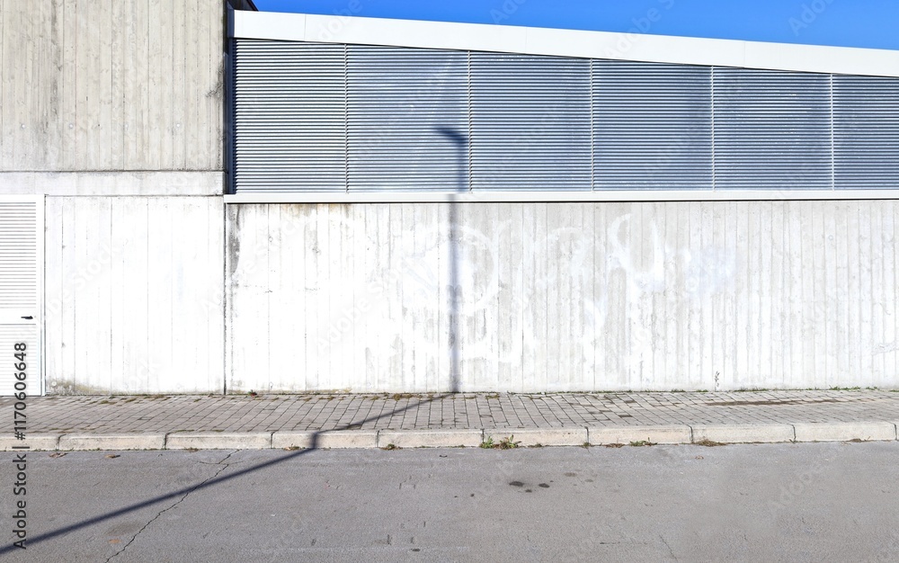 Industrial building made of concrete and metal at the roadside. Cement tiled sidewalk and street in front. Background for copy space. Industrial building made of concrete and metal at the roadside. Cement tiled sidewalk and street in front. Background for copy space.