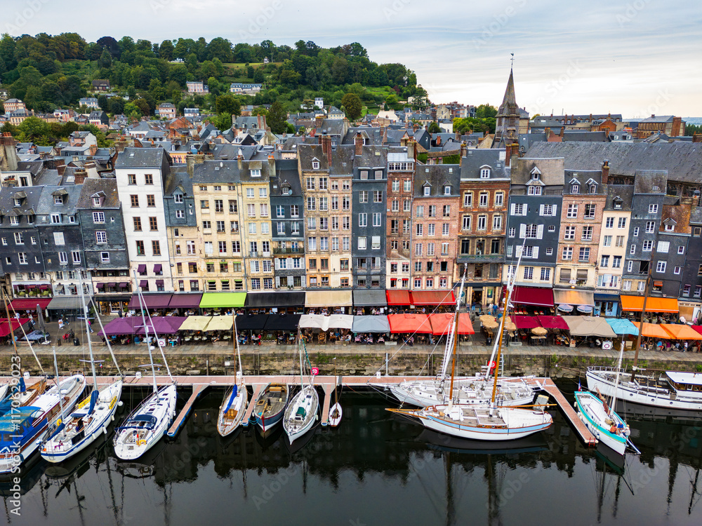 A charming harbor lined with yachts and sailboats surrounded by historic, colorful buildings in a picturesque port town Honfleur, France
