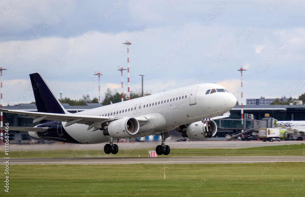 An aircraft preparing to take off from an airport runway, with airport buildings and trees in the background. An aircraft preparing to take off from an airport runway, with airport buildings and trees in the background.