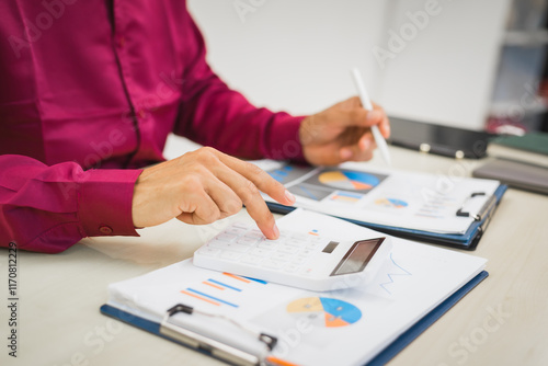 A focused man works diligently in his office, reviewing numerous accounting documents on his desk. His goal is to ensure accuracy and precision, avoiding errors in critical financial data.