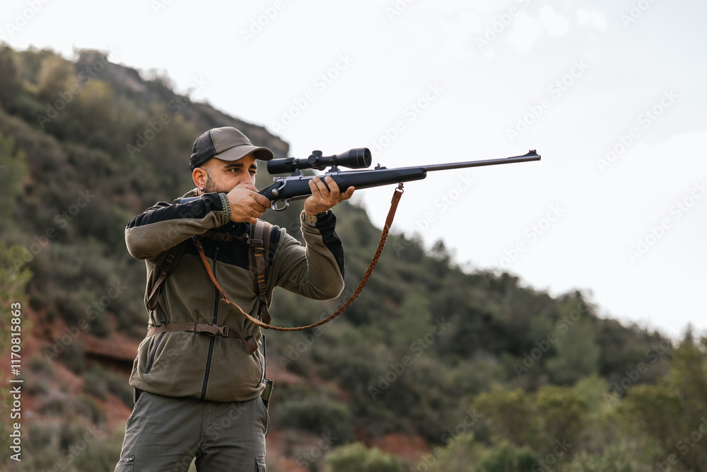 Hunter aiming with rifle in forest during hunt Hunter aiming with rifle in forest during hunt