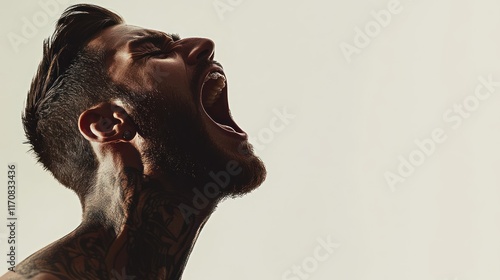 Angry man with tattoos yelling, profile view.