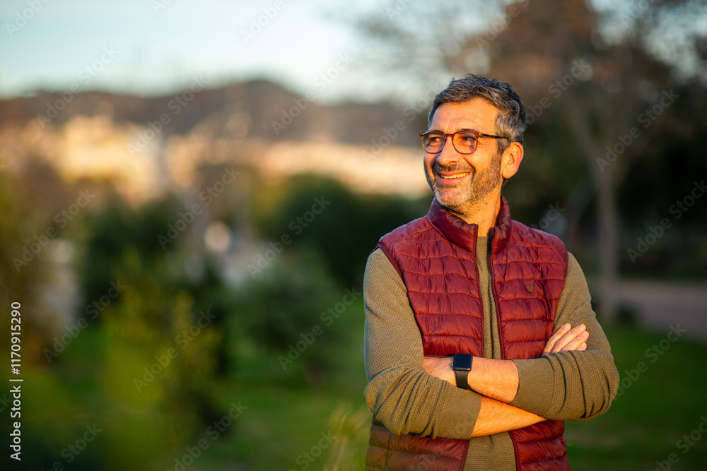 Mature man smiling in a park at sunset Mature man smiling in a park at sunset