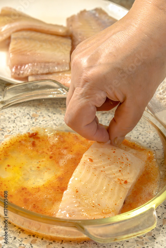 Chef dips a piece of fish into liaison - a mixture of raw eggs, salt, paprika before frying photo