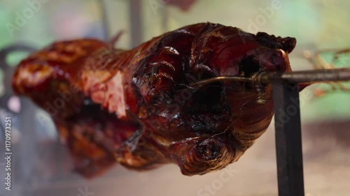 Roasted a whole big pig on fire. Grilled on a big skewer. Roasting piglet on a spit turns slowly roasting it. Barbecue. Street food. 4k. Lechon or Suckling popular dish. pigs roasting on fire pit and 
