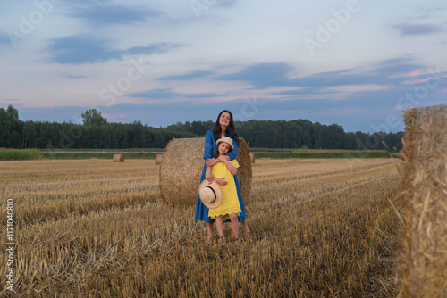 Wallpaper Mural Beautiful Mother and Daughter in a Field with Haystacks at Sunset, Wearing Blue and Yellow Dresses Inspired by the Ukrainian Flag Torontodigital.ca