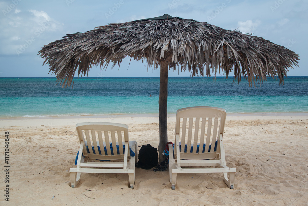 Chairs and a Beach Umbrella and the Caribbean sea pristine waters in Guardalavaca sand beach, Club Amigo Atlantico resort hotel, Cuba