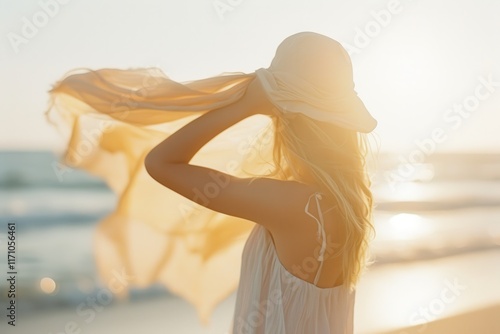 A stylish lifestyle photograph capturing a woman on a sunlit beach, wrapping a flowy scarf around her hair with a carefree spirit. The warm, sun-drenched tones and breezy composition evoke the bohemia
