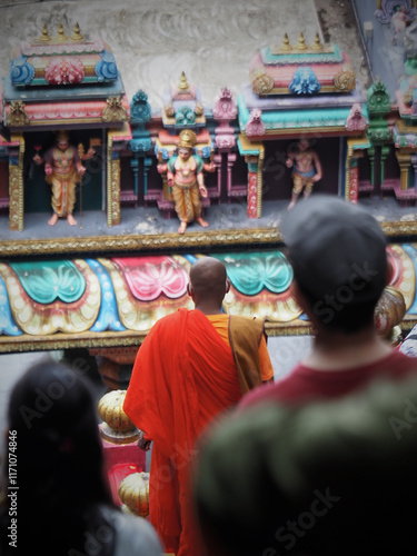 Photography Buddhist monk walking in vibrant orange robe through historic batu caves near ku