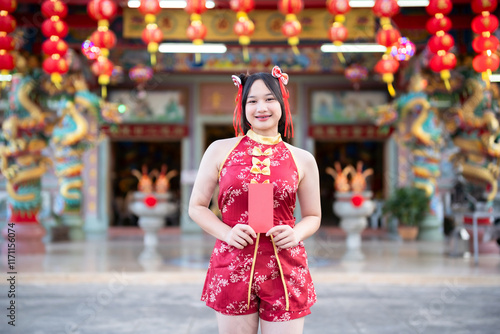 Obraz na płótnie Portrait smiles Asian young woman wearing red cheongsam dress holding red envelopes decoration for Chinese new year festival celebrate culture of china at Chinese shrine Public places in Thailand w salonie