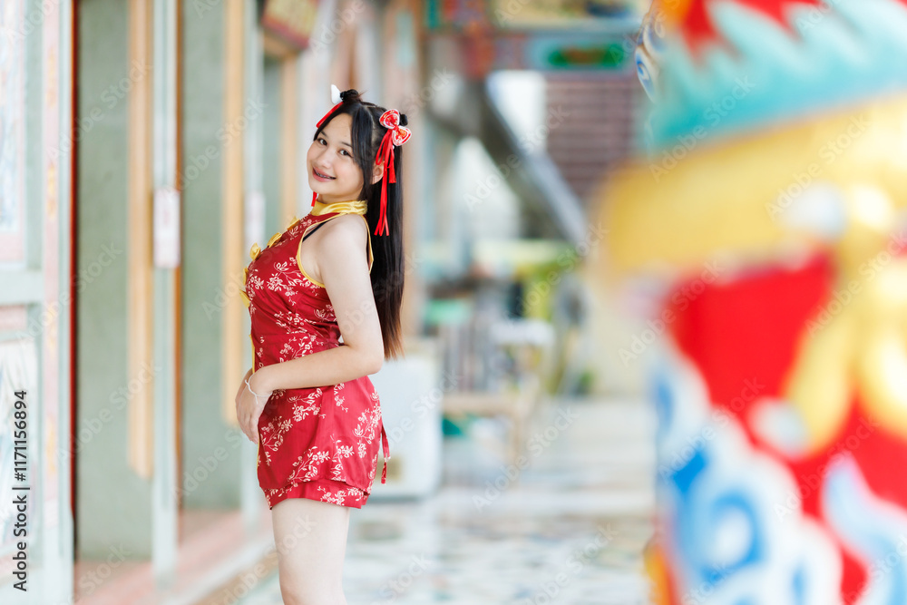 Portrait beautiful cute smiles Asian young woman wearing red cheongsam dress traditional decoration for Chinese new year festival celebrate culture of china at Chinese shrine Public places in Thailand