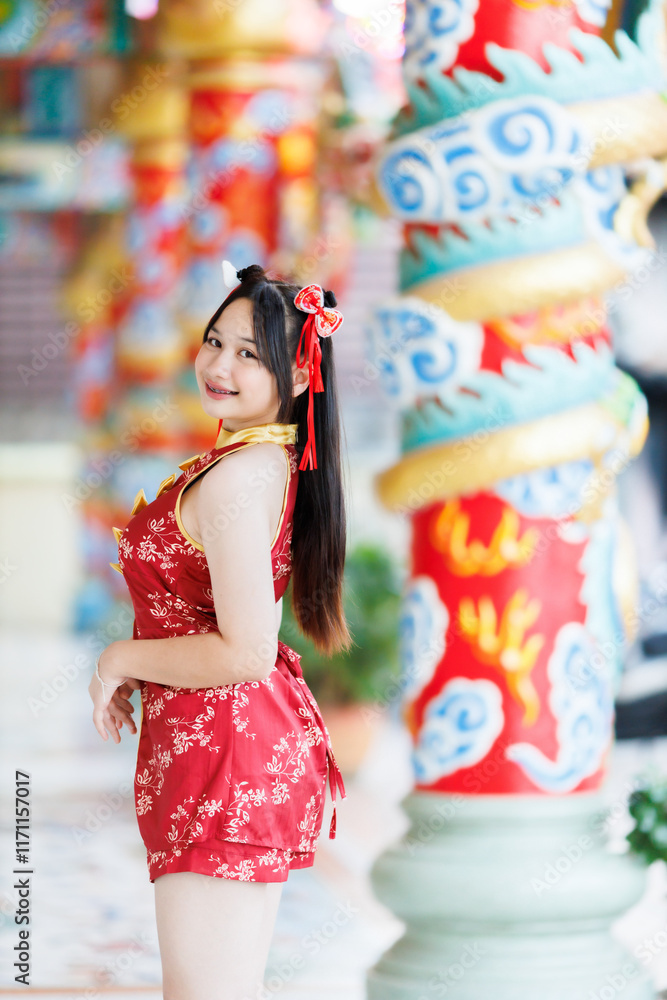 Portrait beautiful cute smiles Asian young woman wearing red cheongsam dress traditional decoration for Chinese new year festival celebrate culture of china at Chinese shrine Public places in Thailand